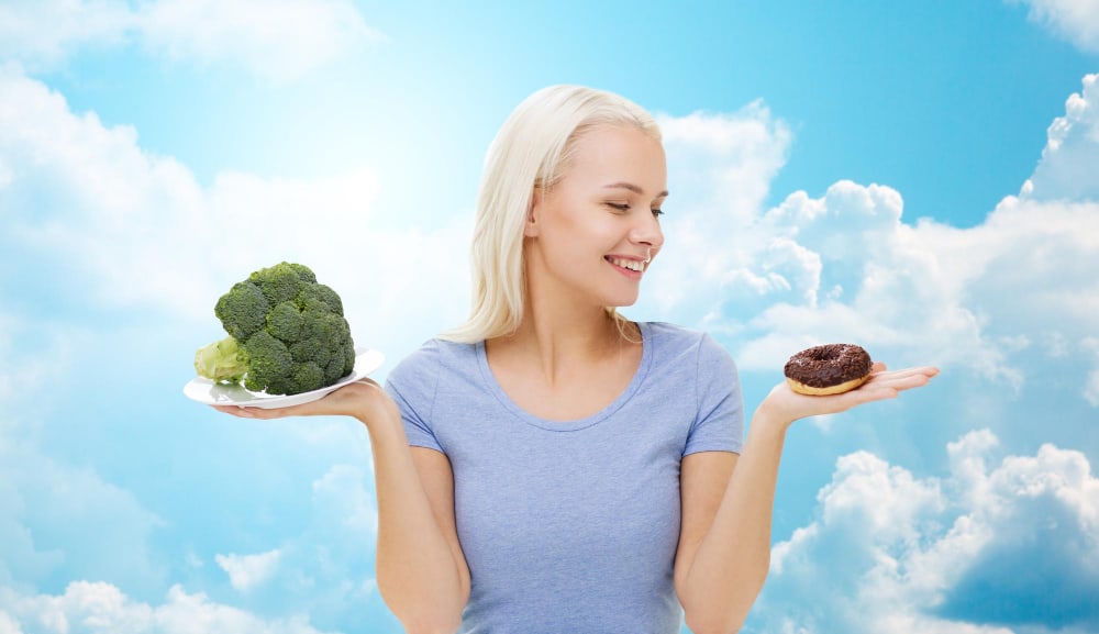 smiling woman choosing broccoli or donut blue sky clouds background