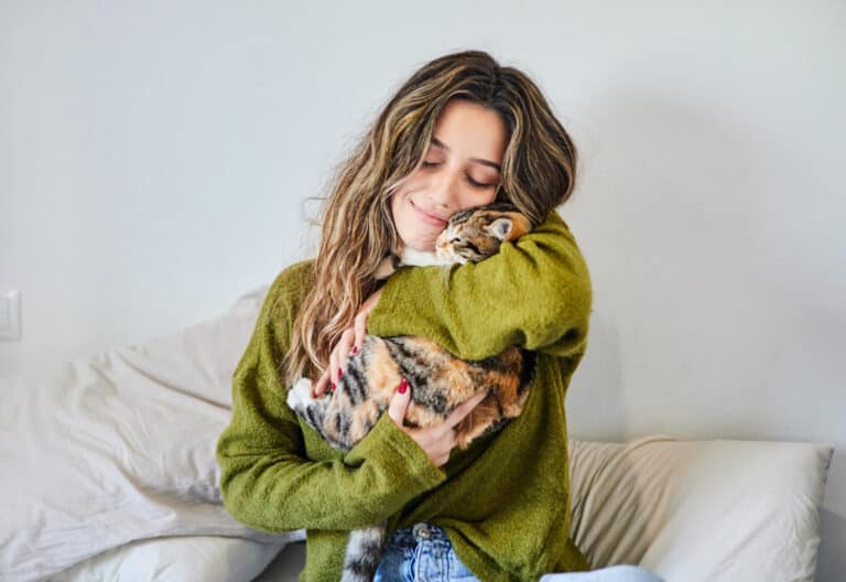 woman hugging her cat on a bed