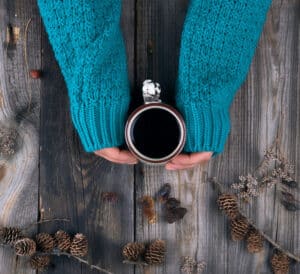 female hands holding ceramic mug with black coffee