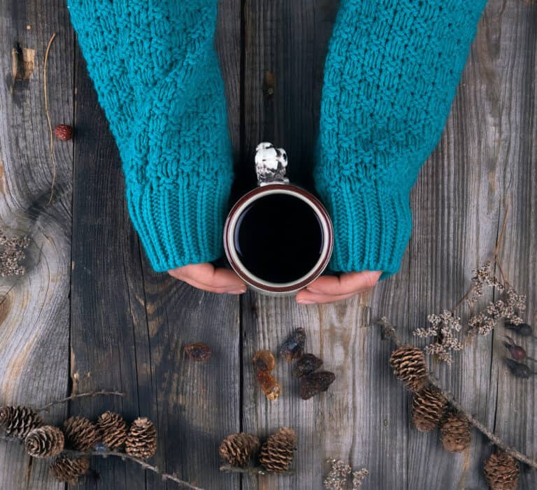 female hands holding ceramic mug with black coffee