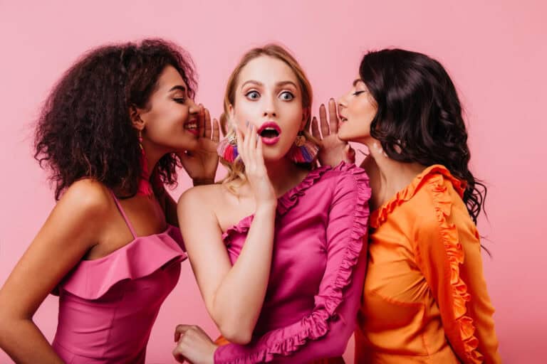 three woman in colorful setting whispering